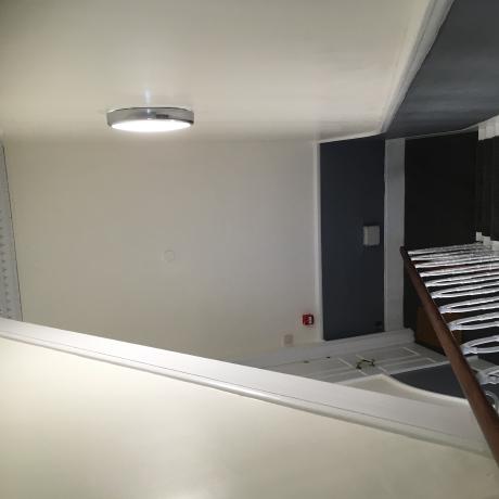 A staircase featuring a professional two-tone paint finish with off-white upper walls and dark blue wainscoting. The image shows clean lines and freshly painted white spindles, demonstrating expert decorating services in Islington, Covent Garden, and Canary Wharf.