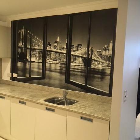 A large, open-plan living area with three white sash windows and professionally painted light grey walls. The high-quality finish on the walls and decorative coving highlights specialist decorating services available in Islington, Covent Garden, and Canary Wharf.